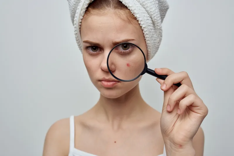 Женщина с увеличительным стеклом в руке в косметологической студии