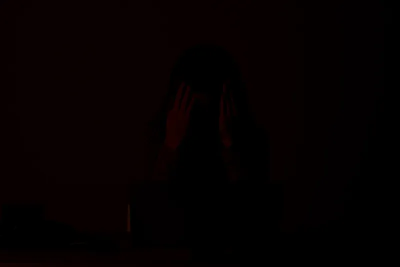 Женщина в наушниках с геймпадом перед ноутбуком сидит за столом, развлечения, образ жизни, розовый фон