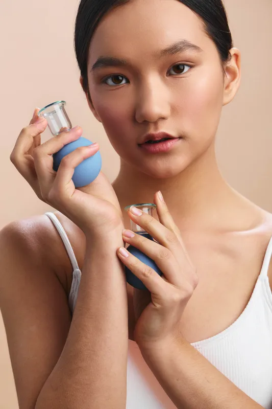 an asian woman is depicted applying skincare product in a clean, everyday setting, exuding calm confidence and gentle focus as she nurtures her routine and glow.