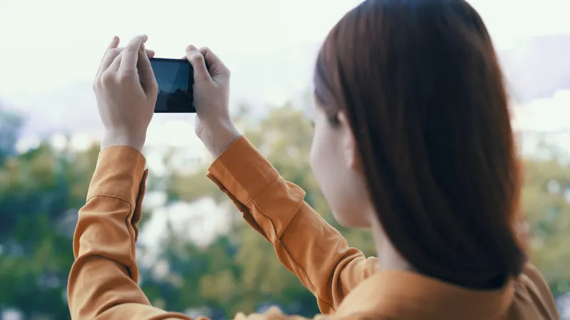 Женщина с телефоном в руках фотографирует природу на открытом воздухе