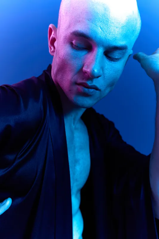 A captivating portrait of a man in a silky robe, showcasing unique lighting that enhances his features. The vibrant blue tones add a modern touch to the black and white theme.