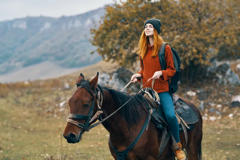 Женщина-туристка едет верхом на лошади на природе в горах
