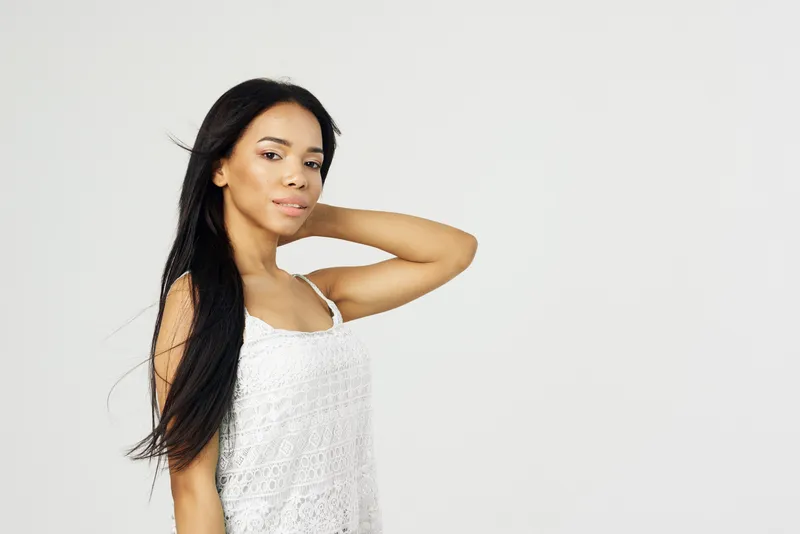 Привлекательная женщина африканской внешности в повседневной жизни позирует с длинными волосами