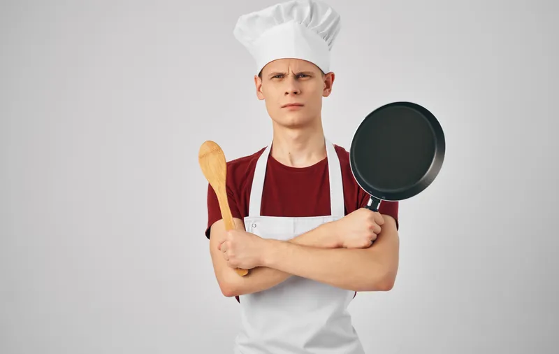 Шеф-повар мужского пола с кухонной утварью готовит еду, сервировка