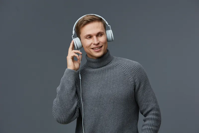 smiling man wearing gray sweater use headphones listen music enjoy leisure digital detox concept studio portrait on gray background