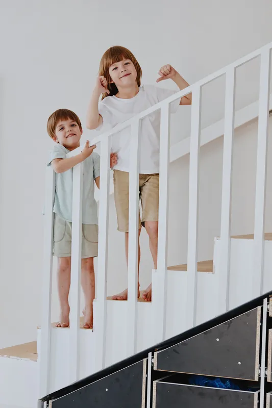 Joyful children play on the staircase, showcasing their playful personalities and vibrant energy in a bright and modern interior space.