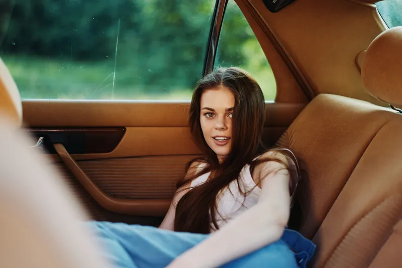 Young woman relaxing in a vintage car, showcasing carefree emotions and natural beauty. Emphasizing a warm color palette and summer vibes, perfect for lifestyle imagery.