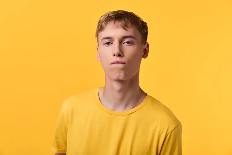 Young man wearing a yellow shirt stands against a bright yellow backdrop, conveying bold simplicity, casual mood, and modern fashion vibe for lifestyle and creative campaigns