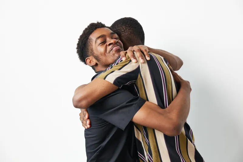 Two black men sharing a warm, joyful embrace, showcasing friendship and connection. Their heartfelt interaction conveys a sense of unity and love, perfect for social themes.