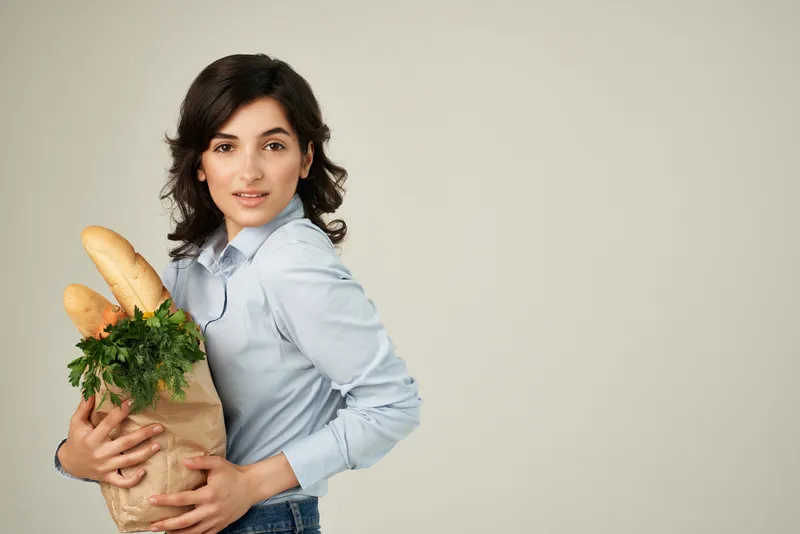 Женщина в синих рубашках с пакетом продуктов в супермаркете