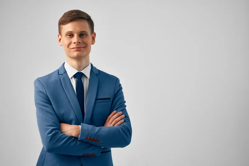 Деловой мужчина в костюме скрестил руки перед собой, демонстрируя уверенность и профессиональный настрой