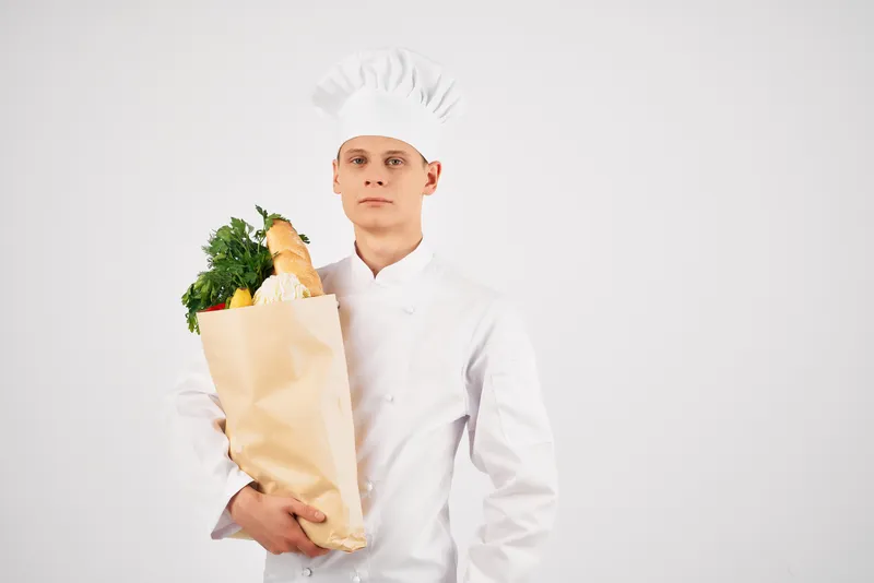 Весёлый мужчина-шеф-повар с упаковкой продуктов на кухне