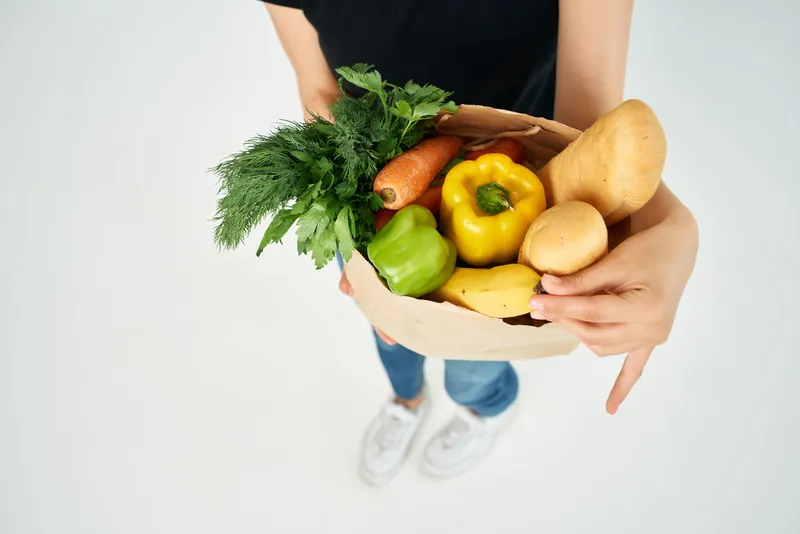 В руке пакет с продуктами, овощи, доставка здоровой пищи