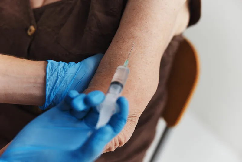 В руке женщины зажат паспорт вакцинации от COVID-19