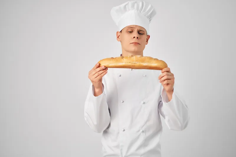 Шеф-повар держит в руке буханку свежего продукта, профессиональный пекарь