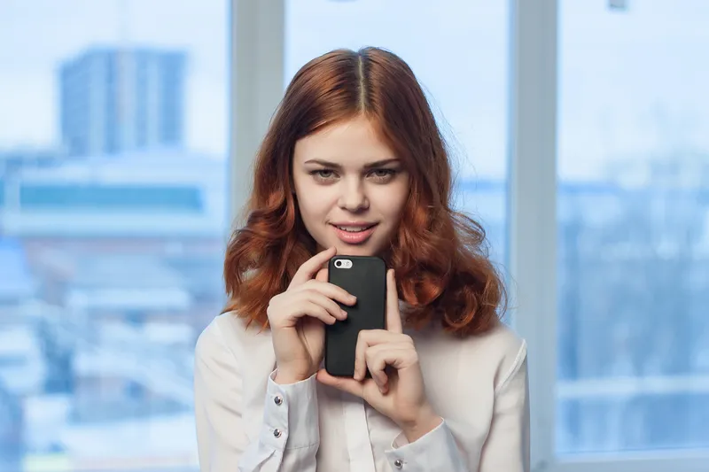 Деловая женщина с телефоном в руках общается в технологичном офисе