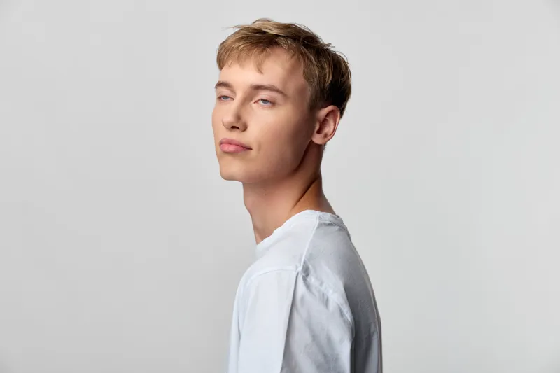 Man with a white shirt, calm side profile against a neutral background, clean and versatile for branding, fashion, or corporate use, showcasing confidence and professionalism.