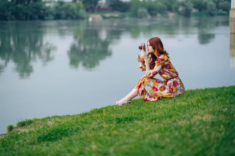 Женщина на открытом воздухе с фотоаппаратом на берегу реки