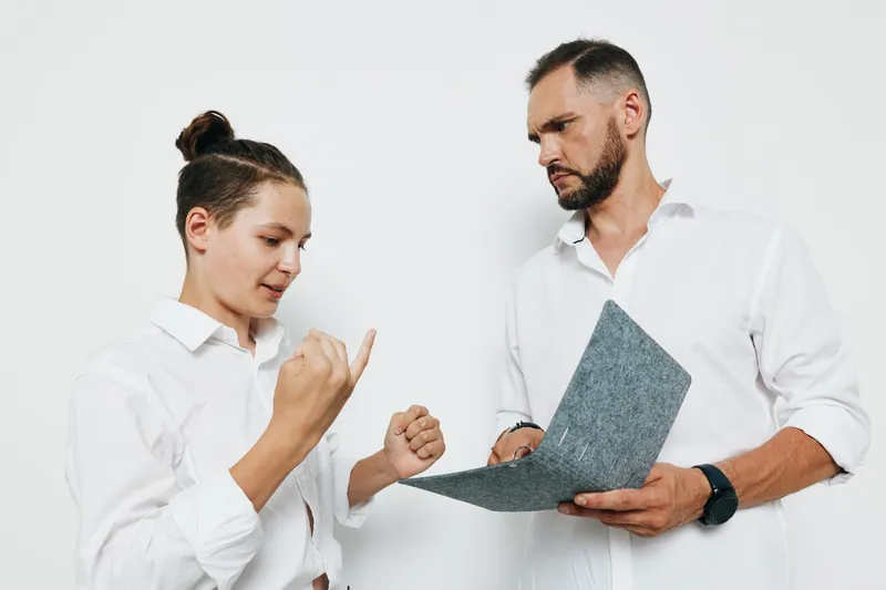 Businessman and professional discuss a document against a solid colored background, showcasing focus, motivation, and collaboration. The scene conveys determination, confidence, and teamwork in a