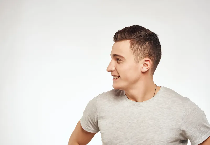 Мужчина в светлой футболке жестикулирует руками, выражая эмоции, крупный план, студия