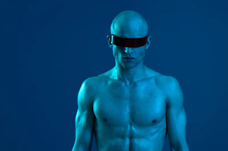 Blue toned man with goggles, showcasing a futuristic aesthetic and bold expression against a vibrant backdrop. A striking representation of modern art in photography.