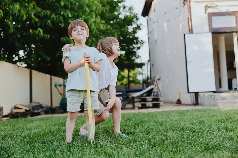 Playful boys enjoying a sunny day outdoors, with a joyful atmosphere and vibrant green grass in the backyard. Perfect for family or children's activities.