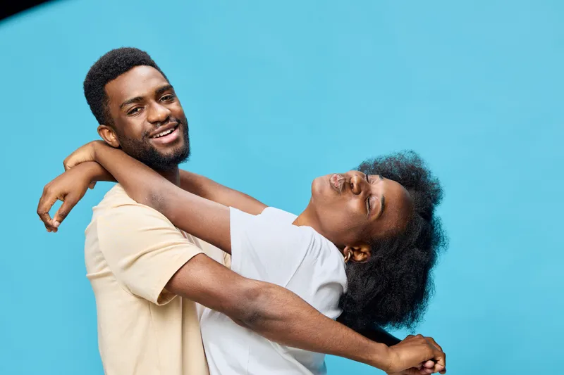 Happy couple embracing on a blue background, showcasing joy and affection in casual summer clothing, perfect for love and relationship themes