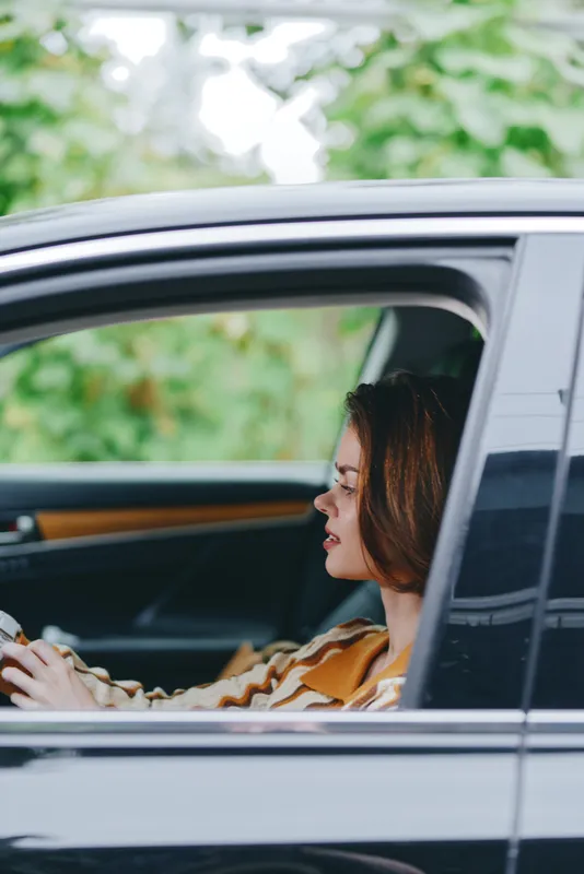 Side profile of a woman sitting in a car, looking ahead with a calm, focused expression and natural light.