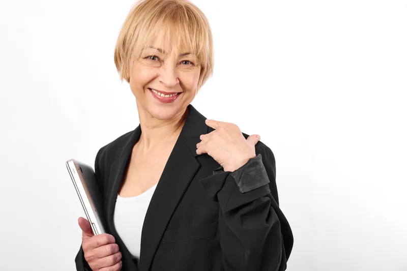 Woman smartphone smile elderly blonde portrait blazer white background, friendly senior holds phone in hand, studio isolated, casual style, technology communication
