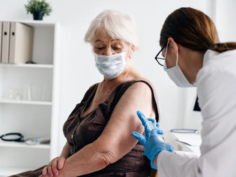 Медсестра делает пациенту укол в плечо, вакцинация от COVID-19, паспорт вакцинации