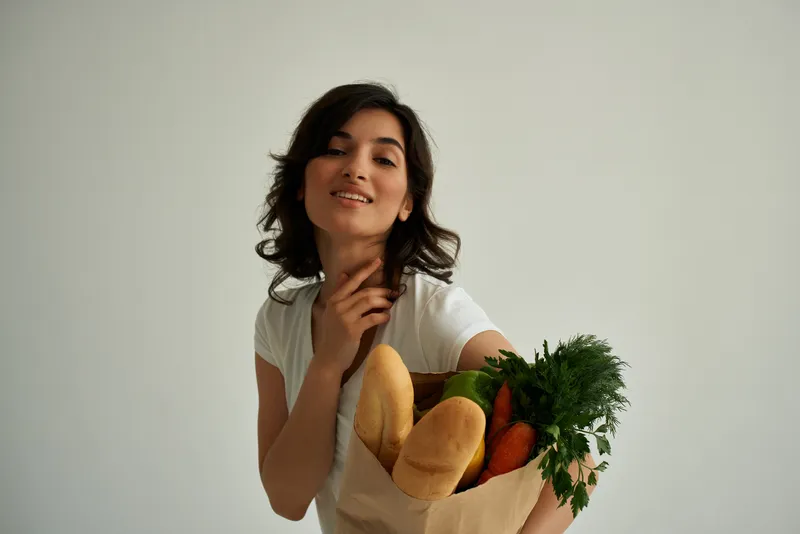 Симпатичная женщина с пакетом продуктов из супермаркета