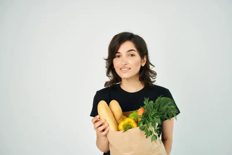 Брюнетка в черной футболке с пакетом продуктов, овощи в супермаркете