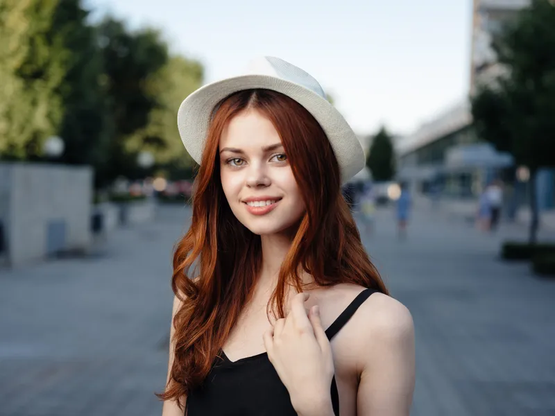 Модная женщина в черном платье идет по улице в парке на природе