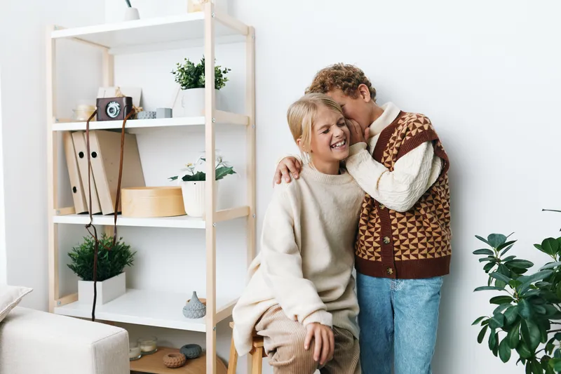 A warm, intimate moment with a smiling couple in cozy sweaters sharing a gentle hug at home, highlighting affection, comfort, and everyday connection.