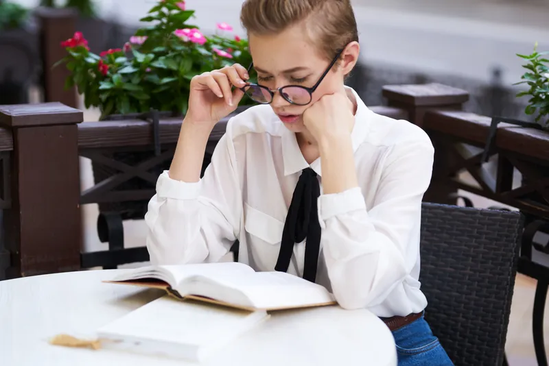 Студент с книгой в руках на открытом воздухе, читает, занимается образованием