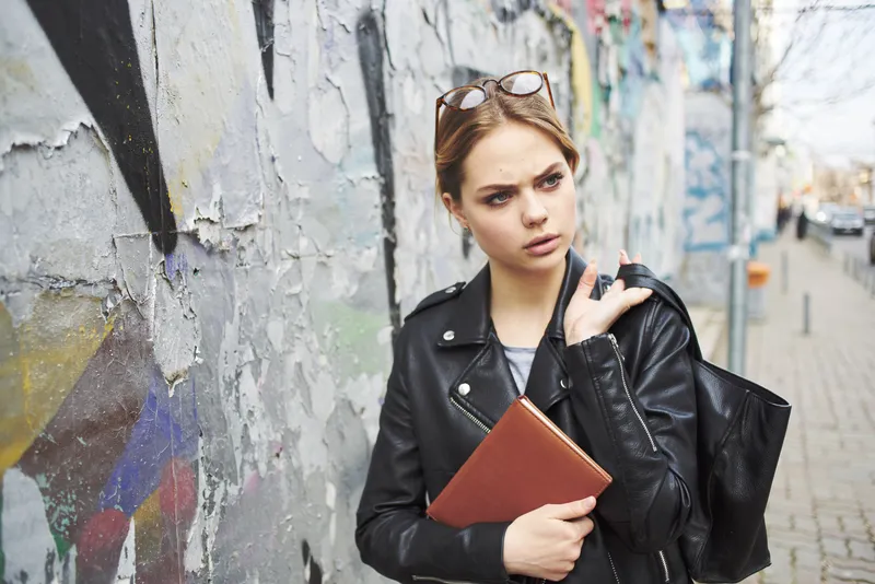 Счастливая женщина читает книгу на улице рядом с граффити на стене