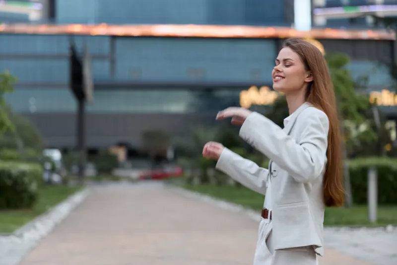 Young woman in beige business suit expressing relief and calm outdoor in urban environment, business, woman, emotion, calm, professional, suit, street