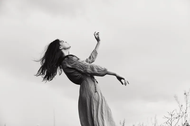Симпатичная женщина в платье жестикулирует руками, позируя в элегантном стиле