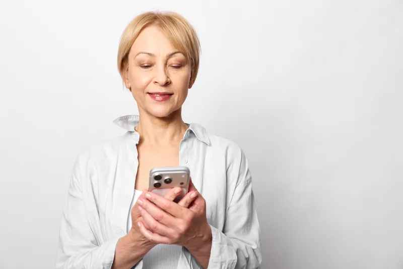 Closeup of a woman holding a smartphone, reading a text, thoughtful expression for technology and internet communication, social connection on a white background