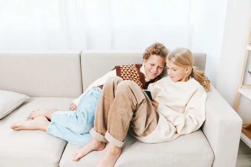 Authentic scene of a family at home, featuring playful learning and a cozy study moment, with school themed activity and relaxed interaction on a soft sofa.
