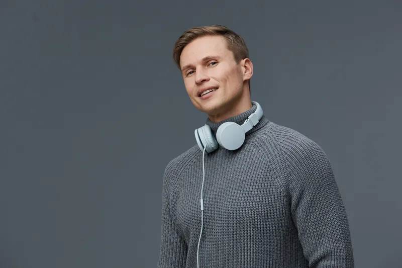 Smiling young man with headphones casual wear looking at camera portrait isolated on gray background studio shot. People lifestyle concept