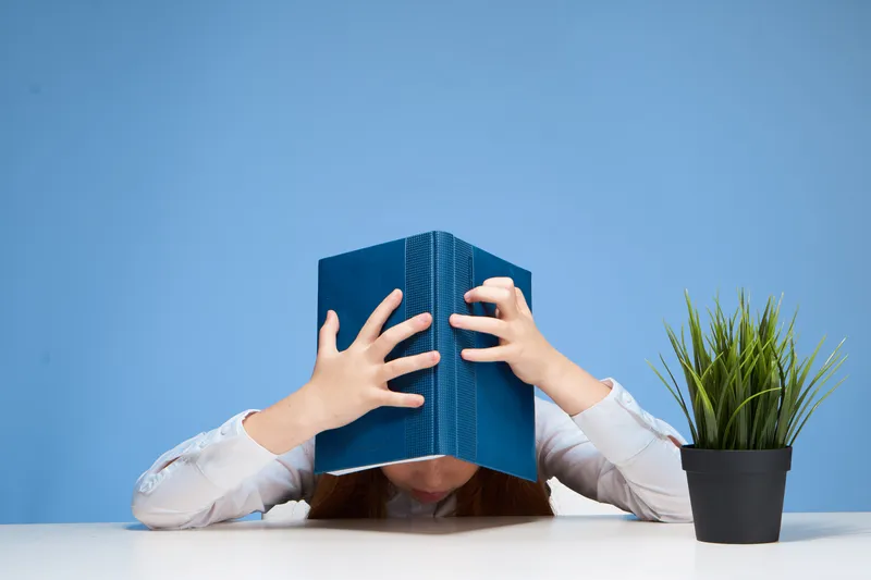 Школьница с книгой на голове, которая учит уроки