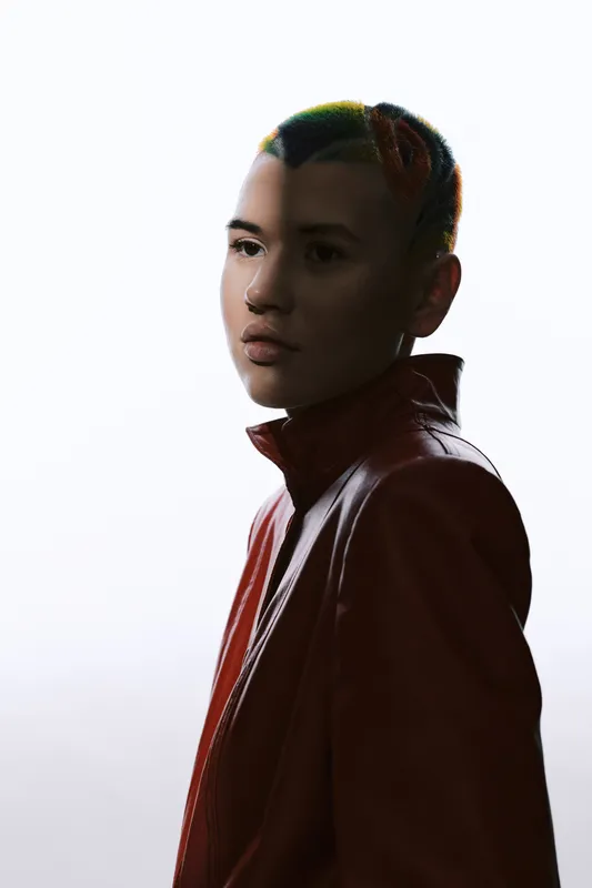 young woman with colorful braided hair in a red jacket facing sideways, minimalistic white background, artistic lighting, modern urban style portrait