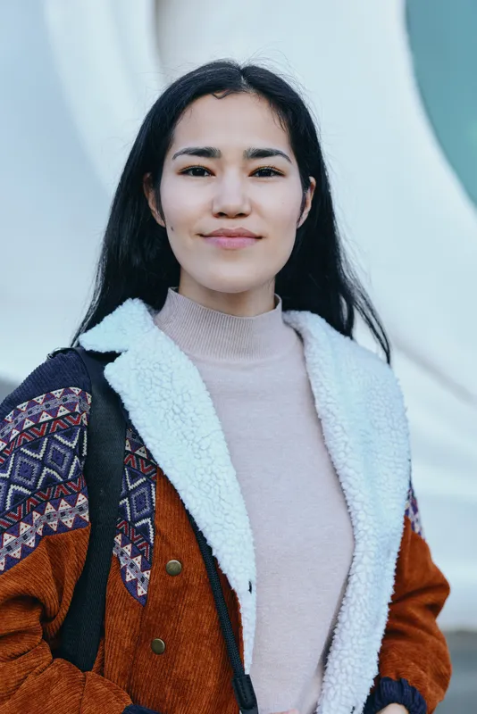 Woman wearing a warm shearling jacket outdoors, casual street style, confident expression, soft background tones, fashion forward look for lifestyle and outerwear
