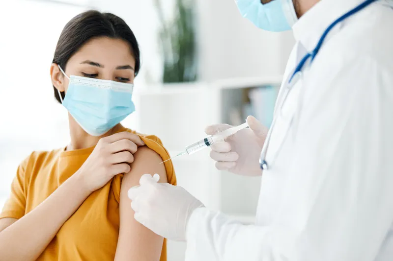 Женщина в медицинской маске на приеме у врача, вакцинация от COVID-19, эпидемия