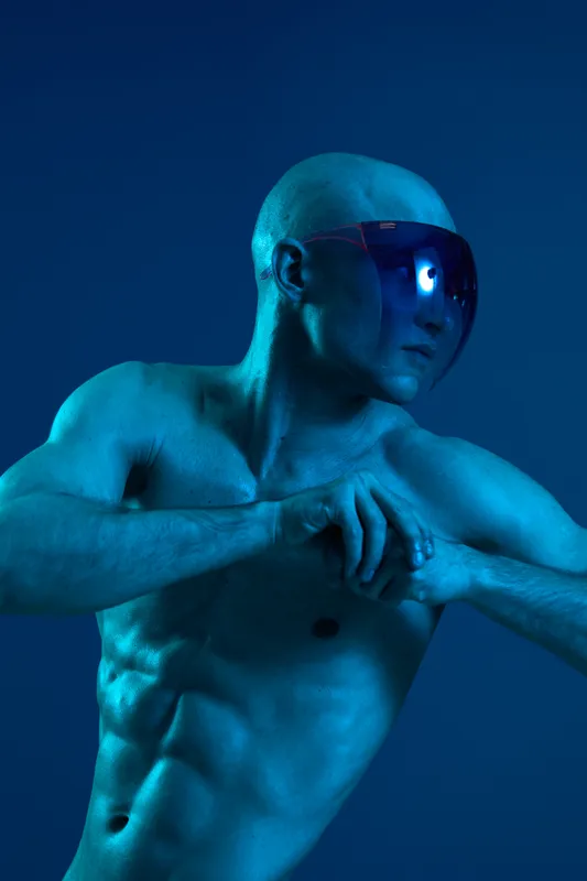 Athletic man with sunglasses poses dramatically against a blue background, showcasing a striking, monochromatic color palette, highlighting strength and style.