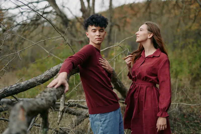 A genuine candid portrait of a young couple in natural autumn surroundings, conveying believable connection and spontaneous interaction, with grounded body language and honest facial expressions.