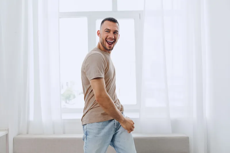 Happy man enjoying a moment of joy in a bright, modern interior, showcasing a trendy lifestyle that reflects the spirit of 2025's creative living trends.