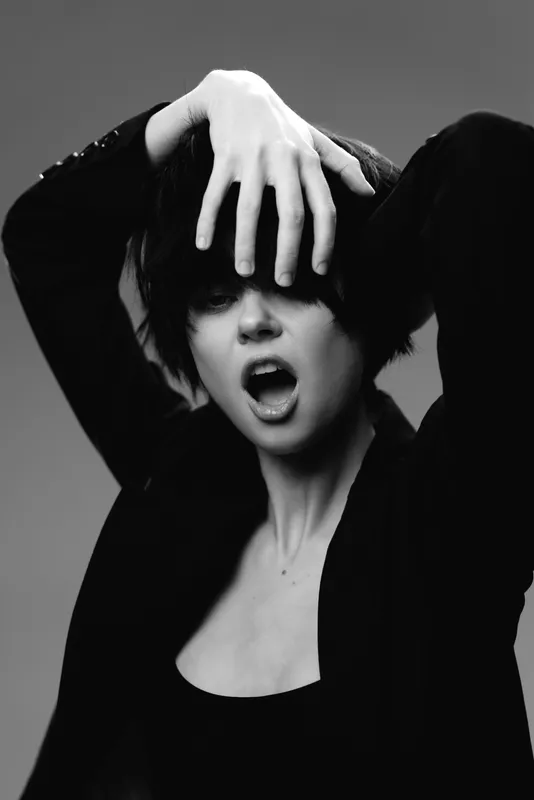 black and white portrait of a young woman with expressive face and hand gesture in studio lighting