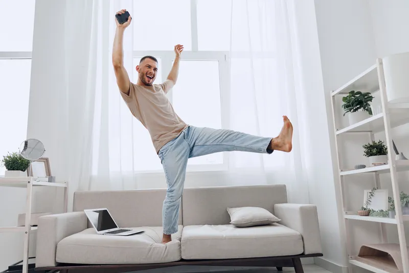 Happy man enjoying a digital detox, embracing his work-life balance at home while celebrating moments of solo living and emotional minimalism.